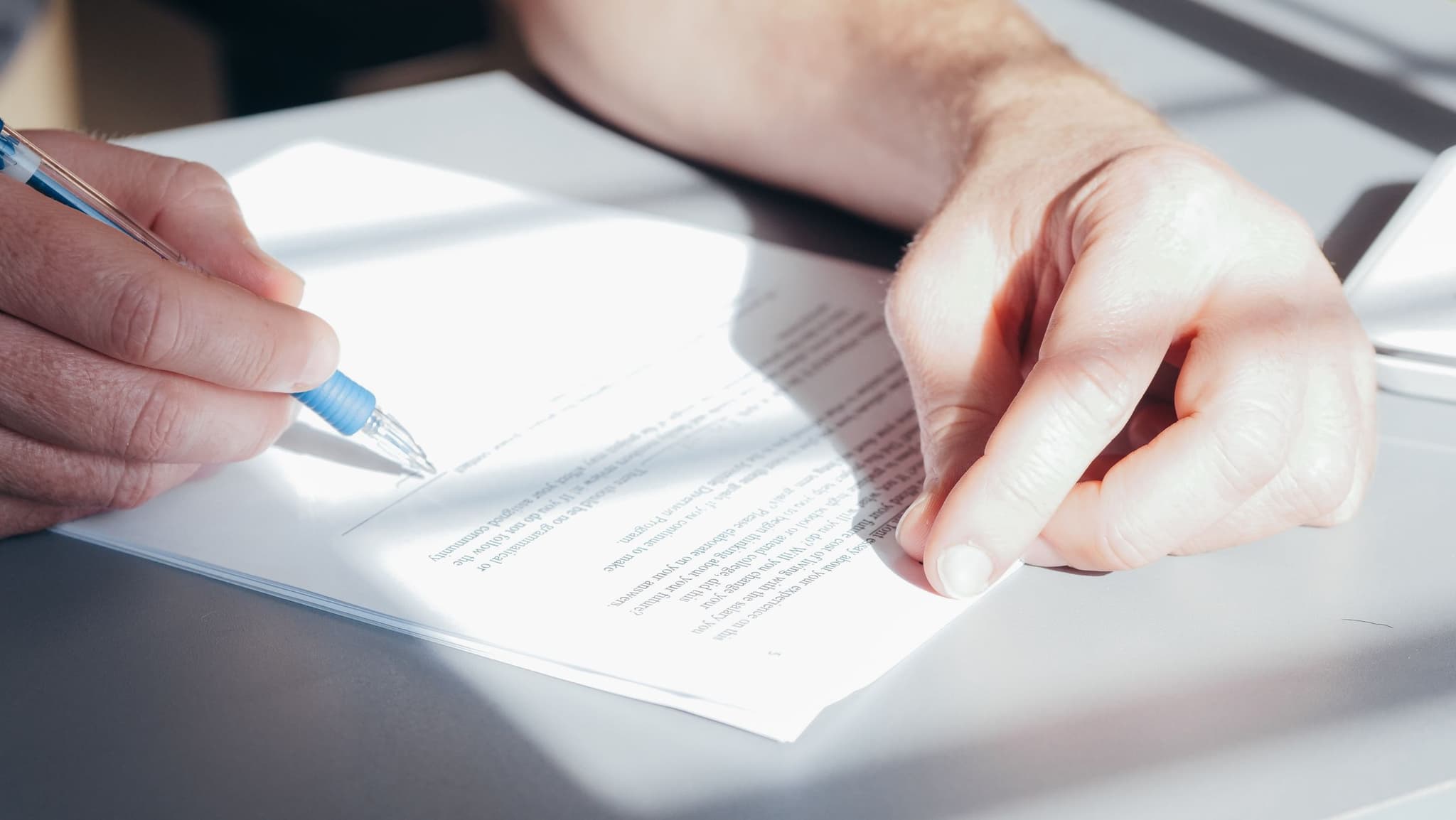 Two hands sign a contract with a pen, close up, at the bilingual notary desk.