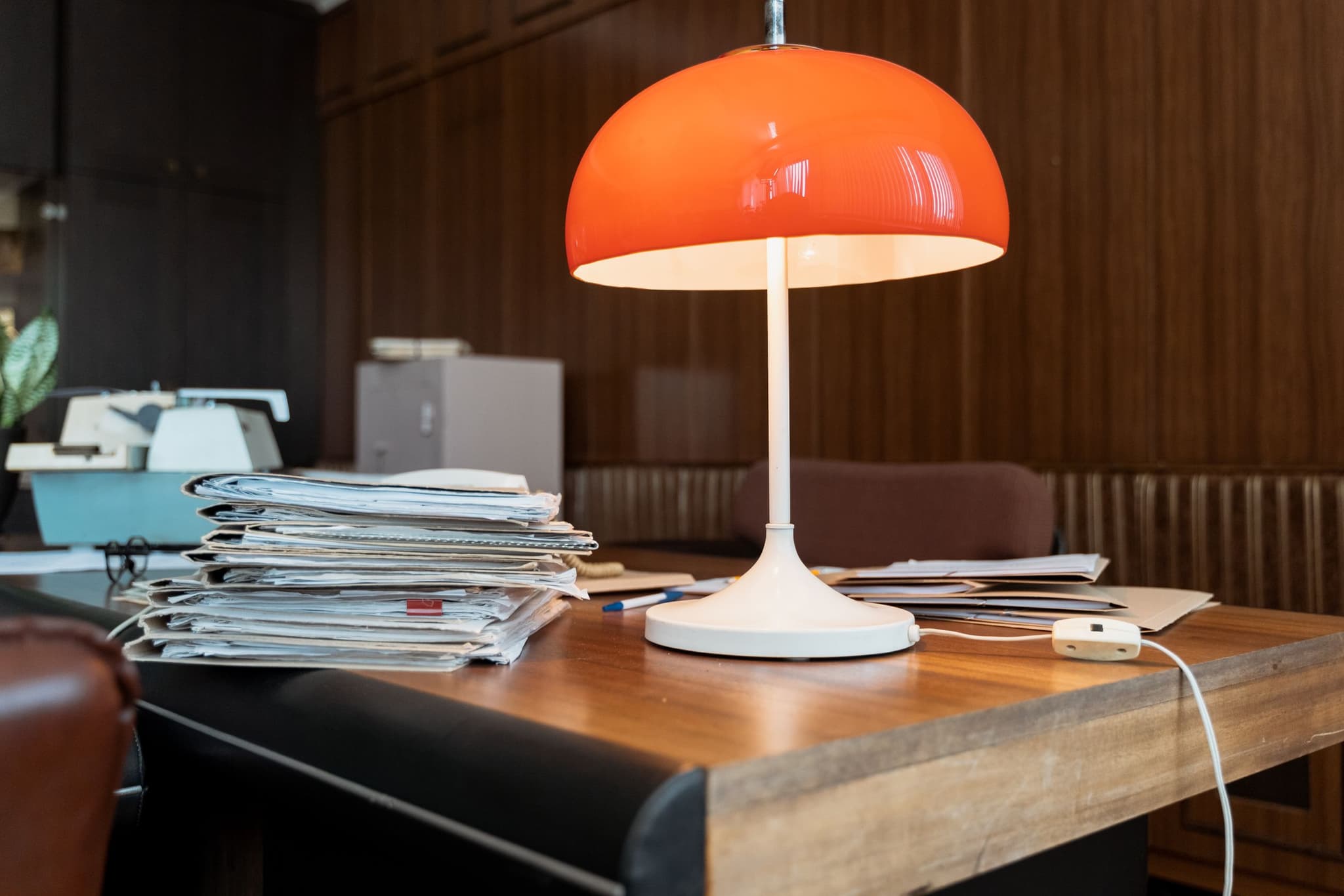 A wooden desk under a warm lamp with folders and the day's paperwork ready.
